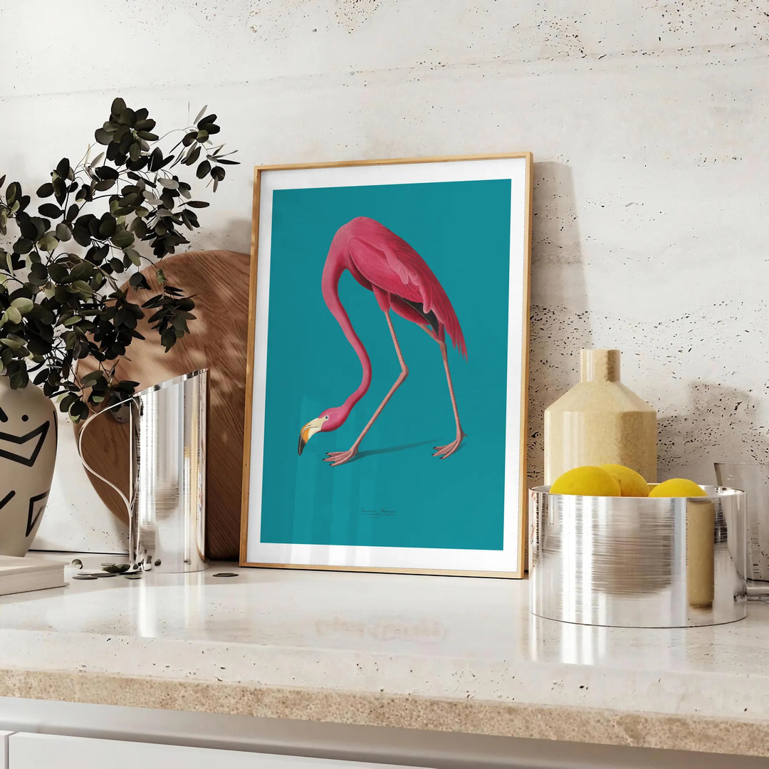 A pink flamingo standing gracefully against a soft blue background - styled on a counter with eucalyptus and a bowl of lemons