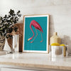 A pink flamingo standing gracefully against a soft blue background - styled on a counter with eucalyptus and a bowl of lemons