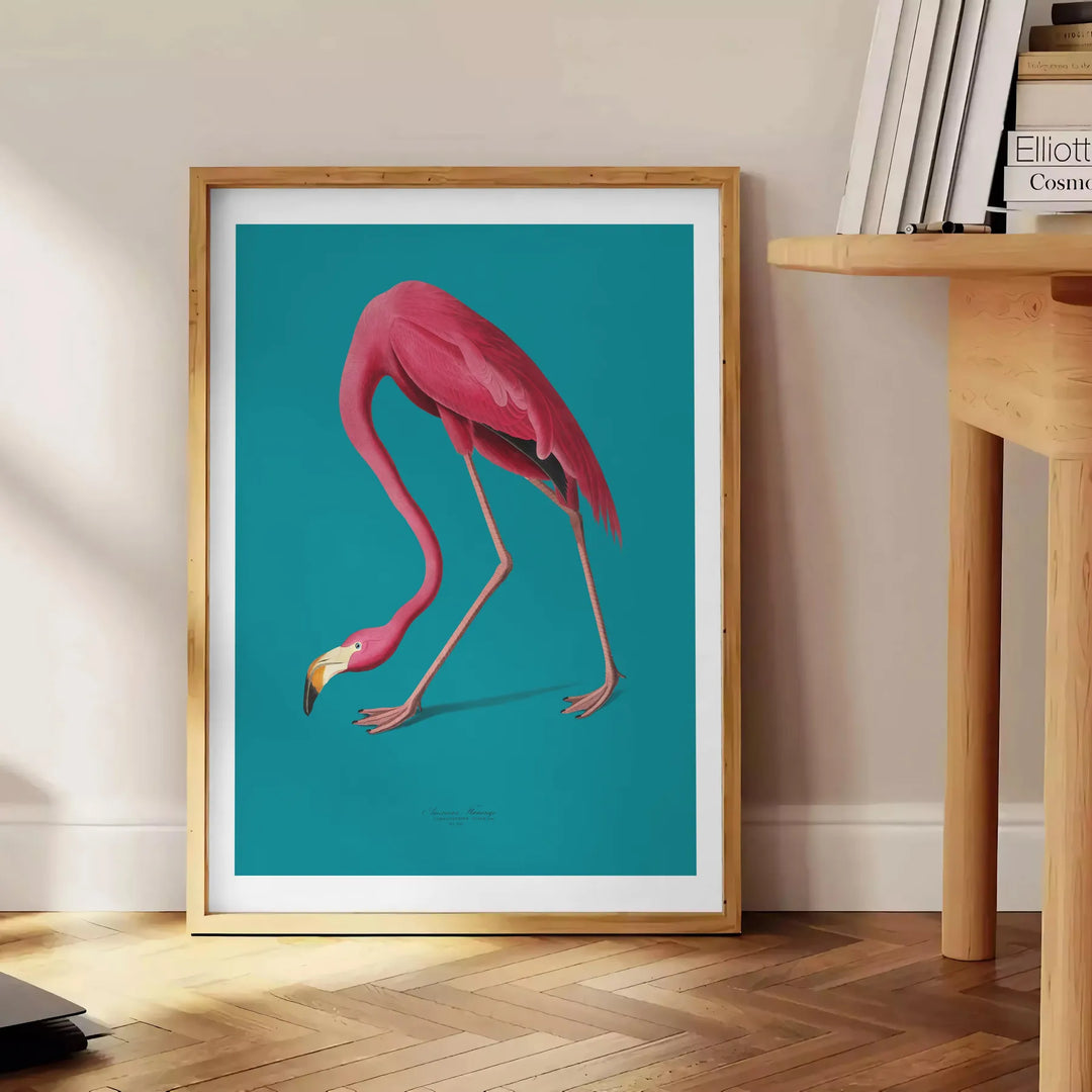 A pink flamingo standing gracefully against a soft blue background - beside a round wooden side table with books