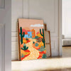 Colorful flower print with green and orange tones in a trendy style - leaning on a herringbone floor against a white panelled wall