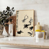 A stylized frog illustration in black and orange, inspired by Matsumoto Hoji, Japan - styled on a counter with eucalyptus and a bowl of lemons