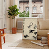 A stylized frog illustration in black and orange, inspired by Matsumoto Hoji, Japan - in a Parisian living room with a sofa and a fig plant