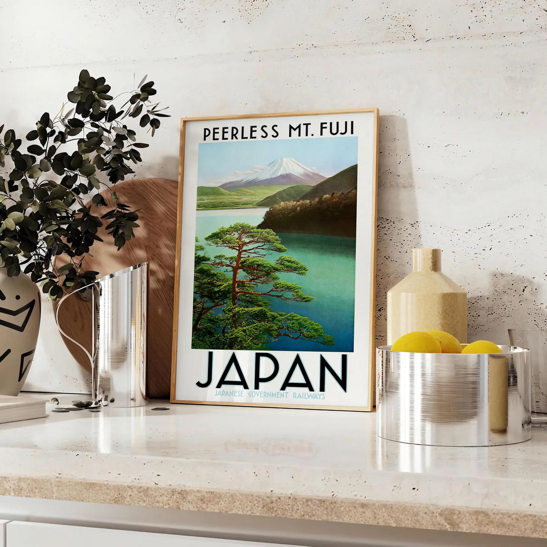 A serene depiction of Mount Fuji surrounded by green hills and gray skies - styled on a counter with eucalyptus and a bowl of lemons