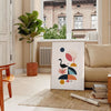 Geometric shapes in black and orange on a minimal background - in a Parisian living room with a sofa and a fig plant