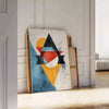 Geometric shapes in orange and blue on a minimal background - leaning on a herringbone floor against a white panelled wall