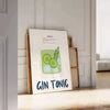 A refreshing gin and tonic with green garnishes on a white background - leaning on a herringbone floor against a white panelled wall