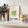 A refreshing gin and tonic with green garnishes on a white background - styled on a counter with eucalyptus and a bowl of lemons