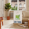 A refreshing gin and tonic with green garnishes on a white background - in a Parisian living room with a sofa and a fig plant