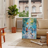 Impressionist landscape with lush greens and blues - in a Parisian living room with a sofa and a fig plant