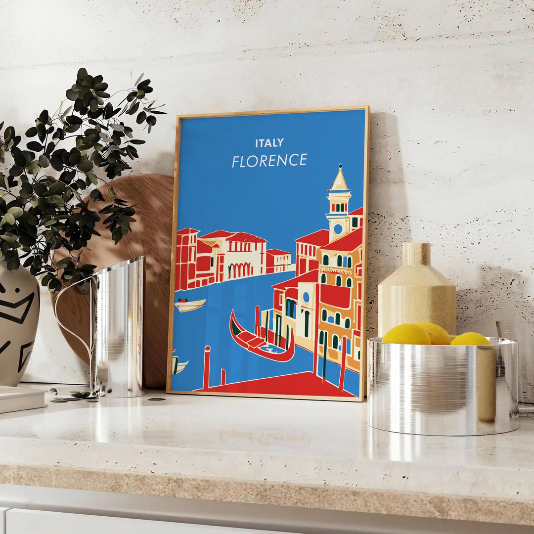 Vintage travel poster featuring Florence, Italy with lush green hills and blue skies - styled on a counter with eucalyptus and a bowl of lemons
