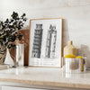 Travel poster featuring the Leaning Tower of Pisa in gray and white tones - styled on a counter with eucalyptus and a bowl of lemons