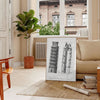 Travel poster featuring the Leaning Tower of Pisa in gray and white tones - in a Parisian living room with a sofa and a fig plant