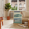 A serene landscape featuring lush green hills and a blue sky in Japan - in a Parisian living room with a sofa and a fig plant