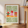 A colorful kitchen print featuring shades of green and orange - beside a round wooden side table with books