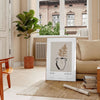 Colorful boho poster featuring abstract shapes and patterns in green and black - in a Parisian living room with a sofa and a fig plant