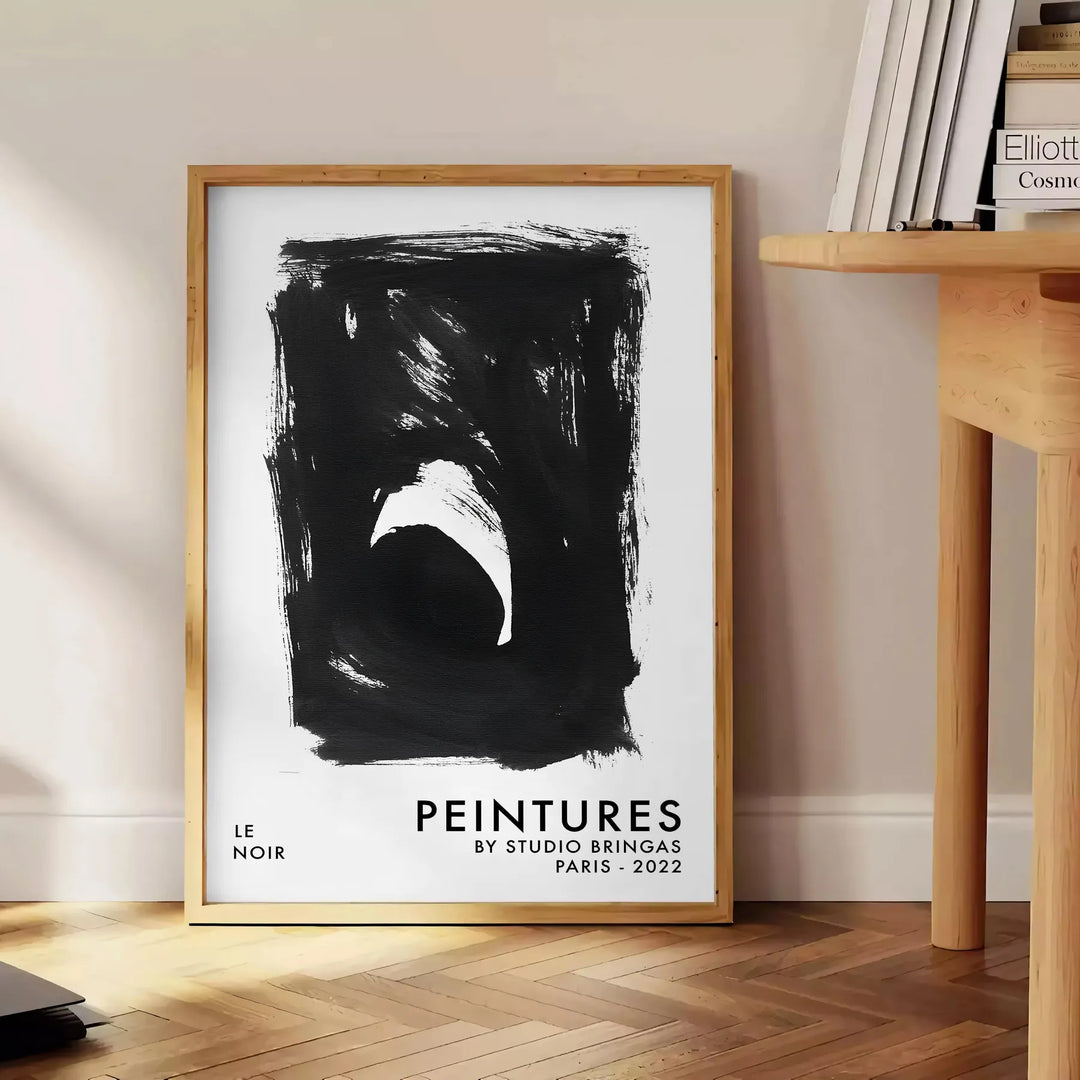 Maximalist poster featuring abstract space elements in black and blue tones - beside a round wooden side table with books