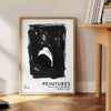 Maximalist poster featuring abstract space elements in black and blue tones - beside a round wooden side table with books