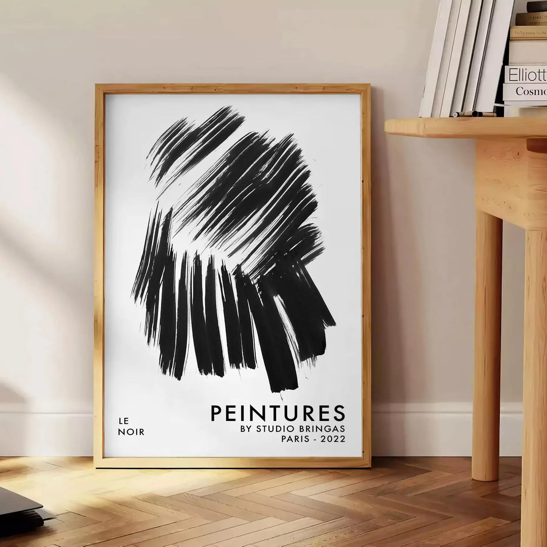 Maximalist wall art featuring bold black and blue hues - beside a round wooden side table with books