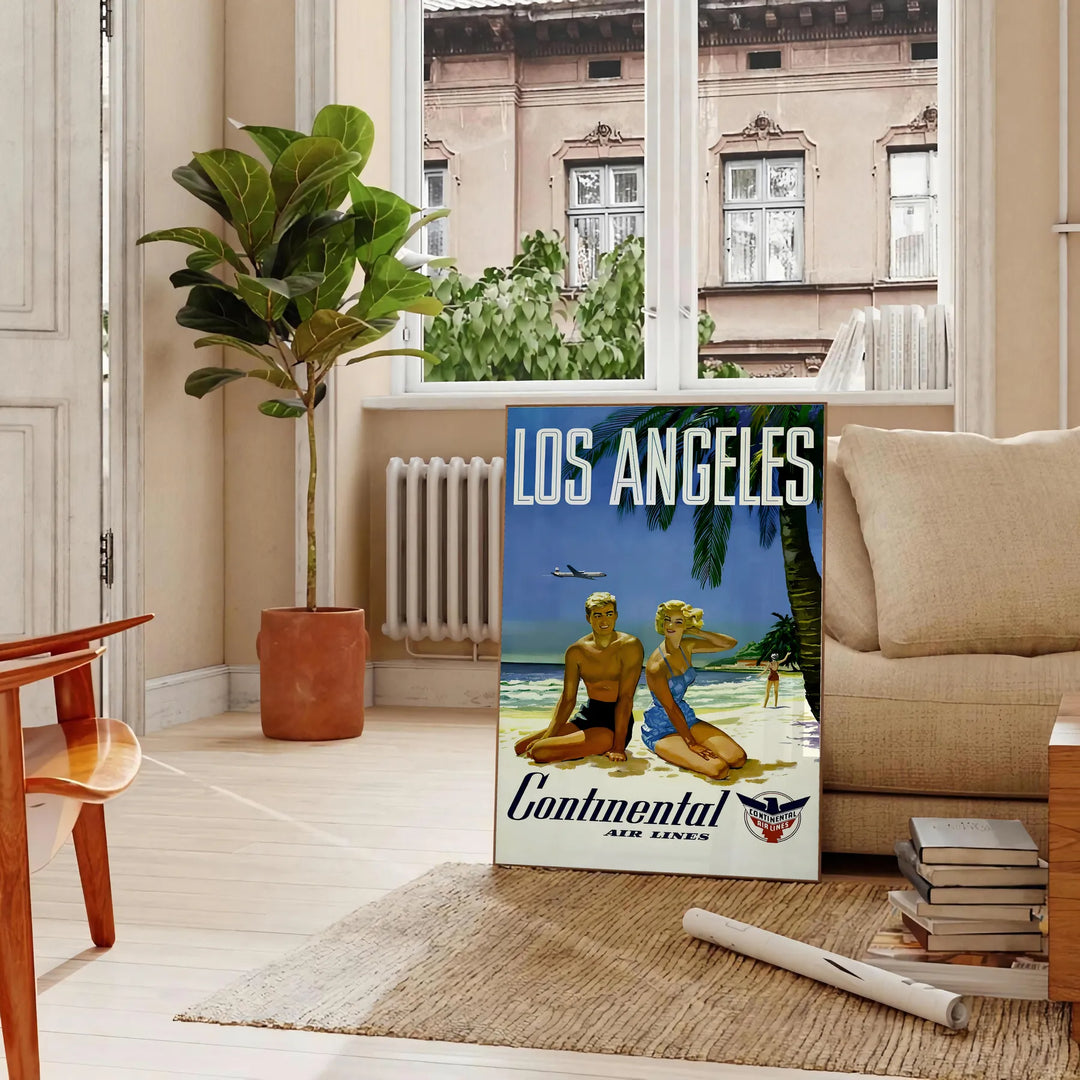 Vintage travel poster featuring Los Angeles with green palm trees and white lettering - in a Parisian living room with a sofa and a fig plant