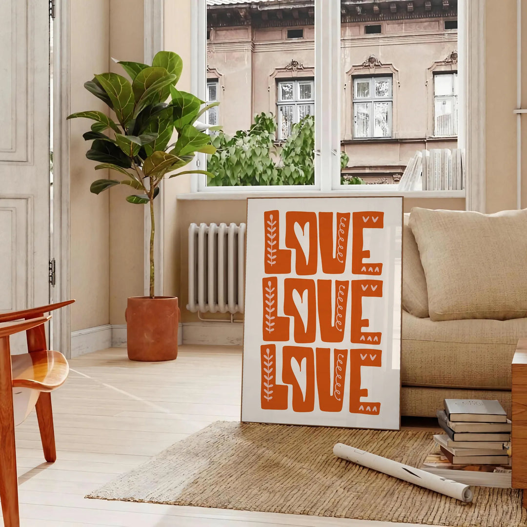 Un poster motivant avec la phrase 'Love Love Love' dans des tons chauds de marron et d'orange - dans un salon parisien avec canapé et ficus