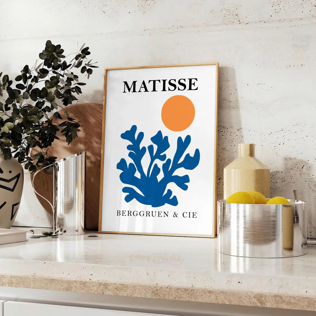 Matisse cut-paper style poster showing abstract black and orange shapes - styled on a counter with eucalyptus and a bowl of lemons
