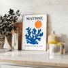 Matisse cut-paper style poster showing abstract black and orange shapes - styled on a counter with eucalyptus and a bowl of lemons
