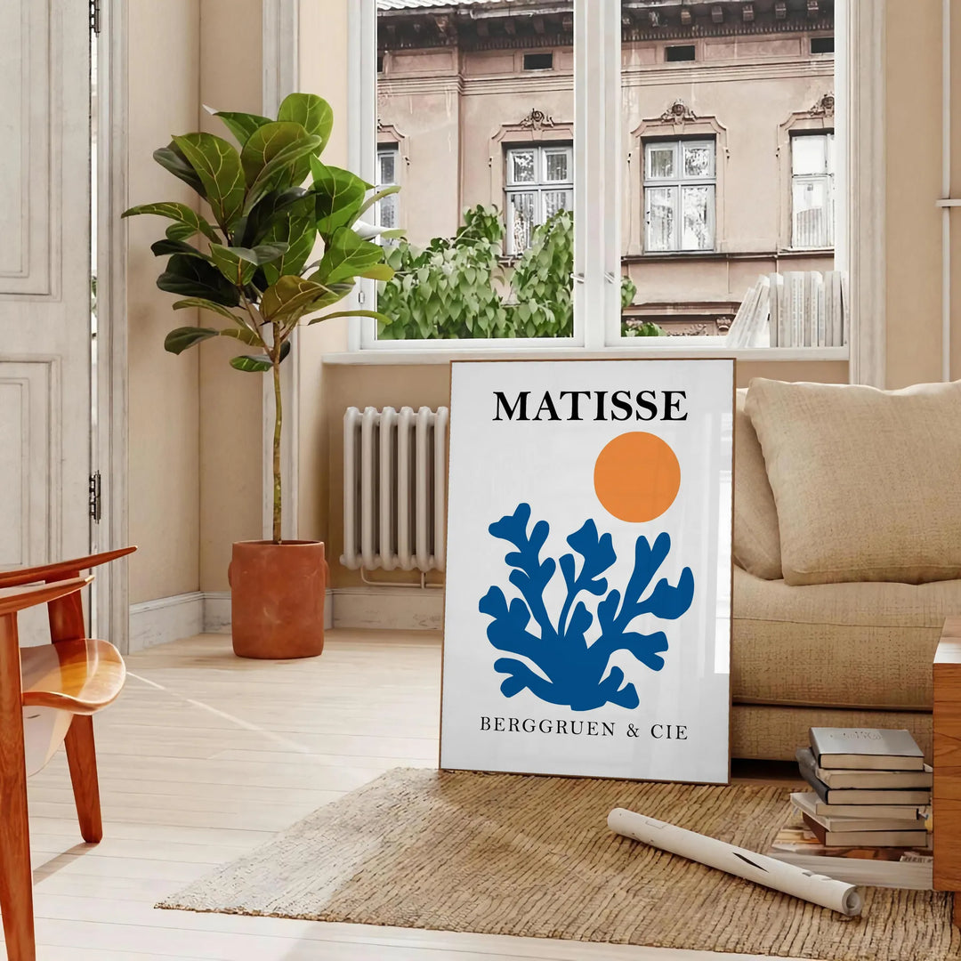 Matisse cut-paper style poster showing abstract black and orange shapes - in a Parisian living room with a sofa and a fig plant