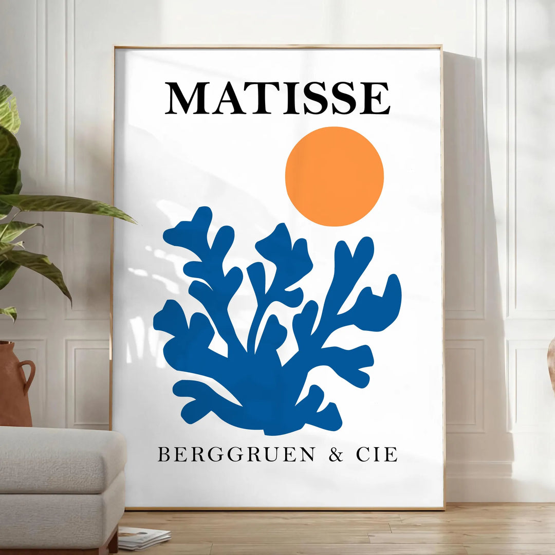 Matisse cut-paper style poster showing abstract black and orange shapes - in a bright minimalist room with a plant and an armchair