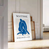 Gray and white Matisse papier découpés poster with abstract organic shapes - leaning on a herringbone floor against a white panelled wall