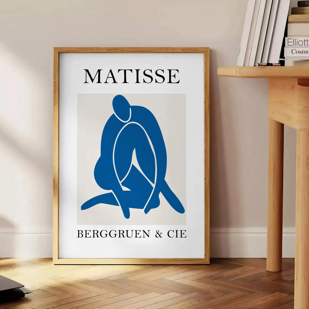 Gray and white Matisse papier découpés poster with abstract organic shapes - beside a round wooden side table with books