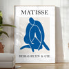 Gray and white Matisse papier découpés poster with abstract organic shapes - in a bright minimalist room with a plant and an armchair