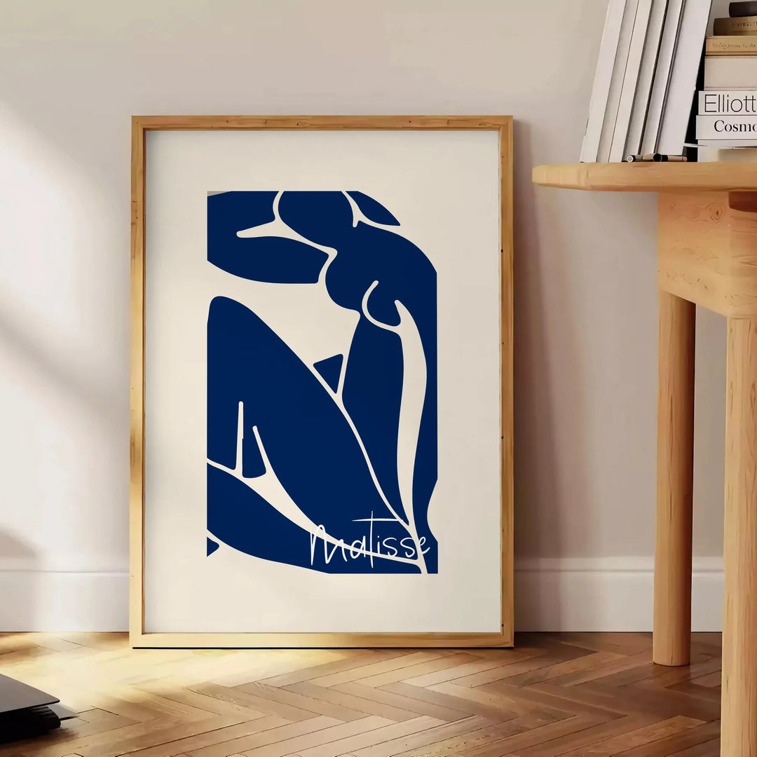 Gray and white cut-out shapes in Matisse's papier découpés style - beside a round wooden side table with books
