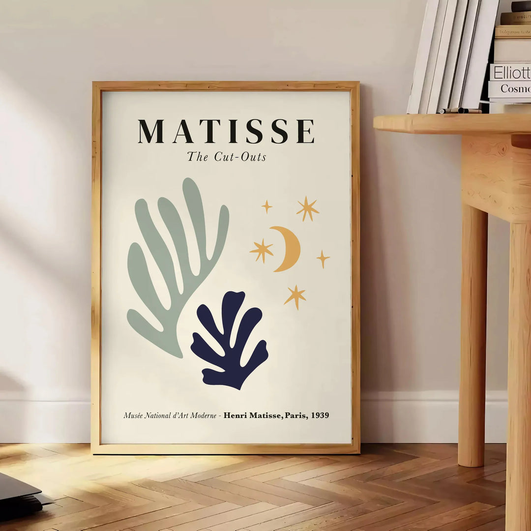 Abstract cut-out shapes in bold colors inspired by Matisse - beside a round wooden side table with books