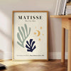 Abstract cut-out shapes in bold colors inspired by Matisse - beside a round wooden side table with books