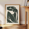 Gray and white poster of Matisse paper cut abstract shapes, minimalist. - beside a round wooden side table with books