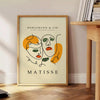 Poster of Matisse-style papier découpé abstract composition, bold organic shapes - beside a round wooden side table with books