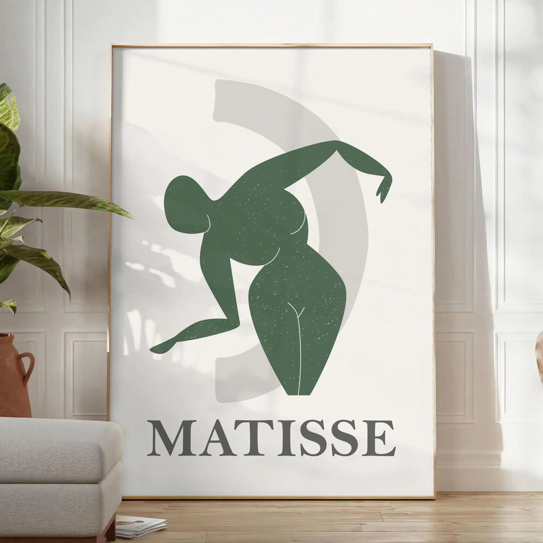 Plakāts bez rāmja ar krāsainu Matisse darbu grieztā papīra tehnikā, abstraktas formas - gaišā minimālistiskā istabā ar augu un atzveltnes krēslu