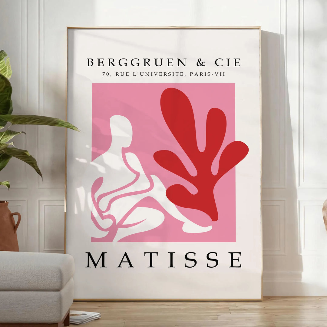Poster showing Matisse-style papier découpé abstract red and gray shapes - in a bright minimalist room with a plant and an armchair