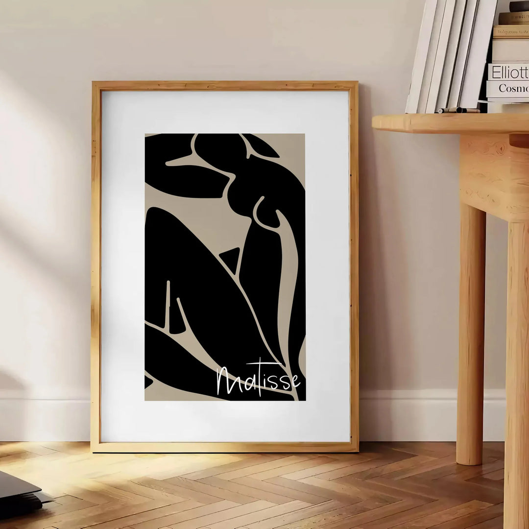 Poster showing Matisse-style abstract cut-out shapes in bold colors - beside a round wooden side table with books