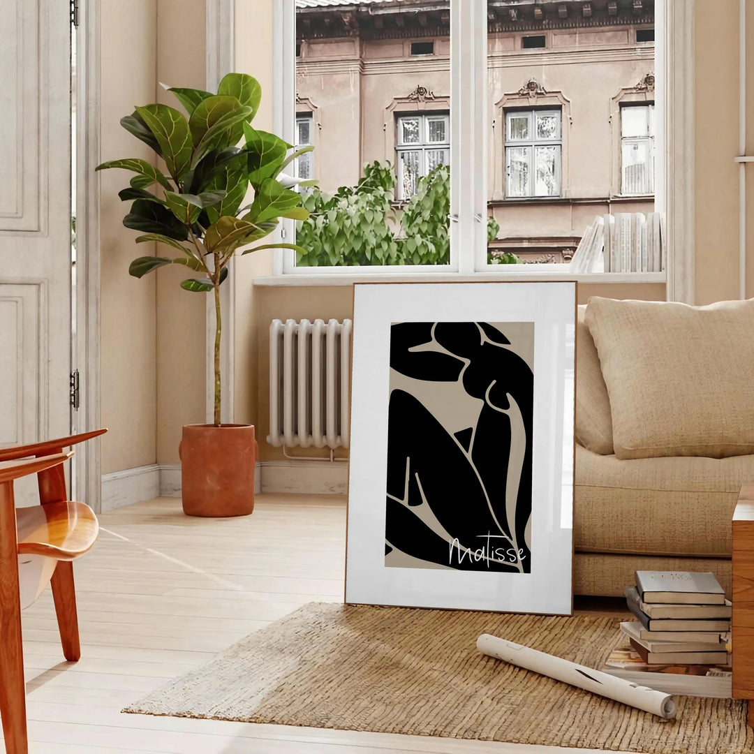 Poster showing Matisse-style abstract cut-out shapes in bold colors - in a Parisian living room with a sofa and a fig plant