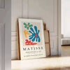 Abstract cut-out design in white and yellow by Matisse - leaning on a herringbone floor against a white panelled wall