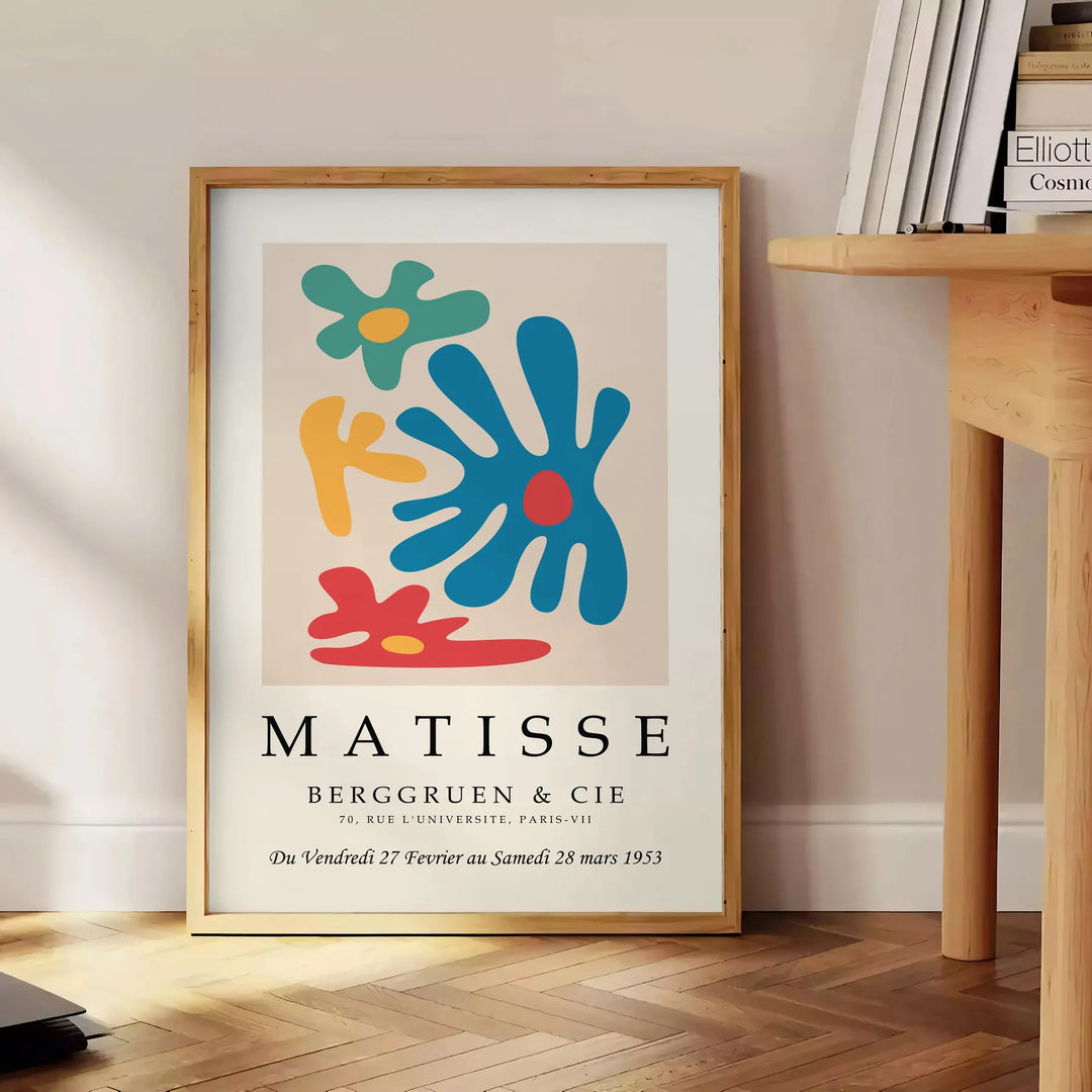 Abstract cut-out design in white and yellow by Matisse - beside a round wooden side table with books