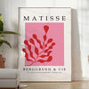 Abstract cut-paper collage by Matisse featuring gray and red shapes - in a bright minimalist room with a plant and an armchair