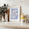 Poster showing Matisse paper cut-out artwork in bold abstract shapes - styled on a counter with eucalyptus and a bowl of lemons