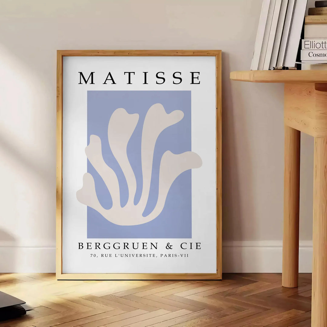 Poster showing Matisse paper cut-out artwork in bold abstract shapes - beside a round wooden side table with books