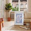 Poster showing Matisse paper cut-out artwork in bold abstract shapes - in a Parisian living room with a sofa and a fig plant