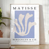 Poster showing Matisse paper cut-out artwork in bold abstract shapes - in a bright minimalist room with a plant and an armchair