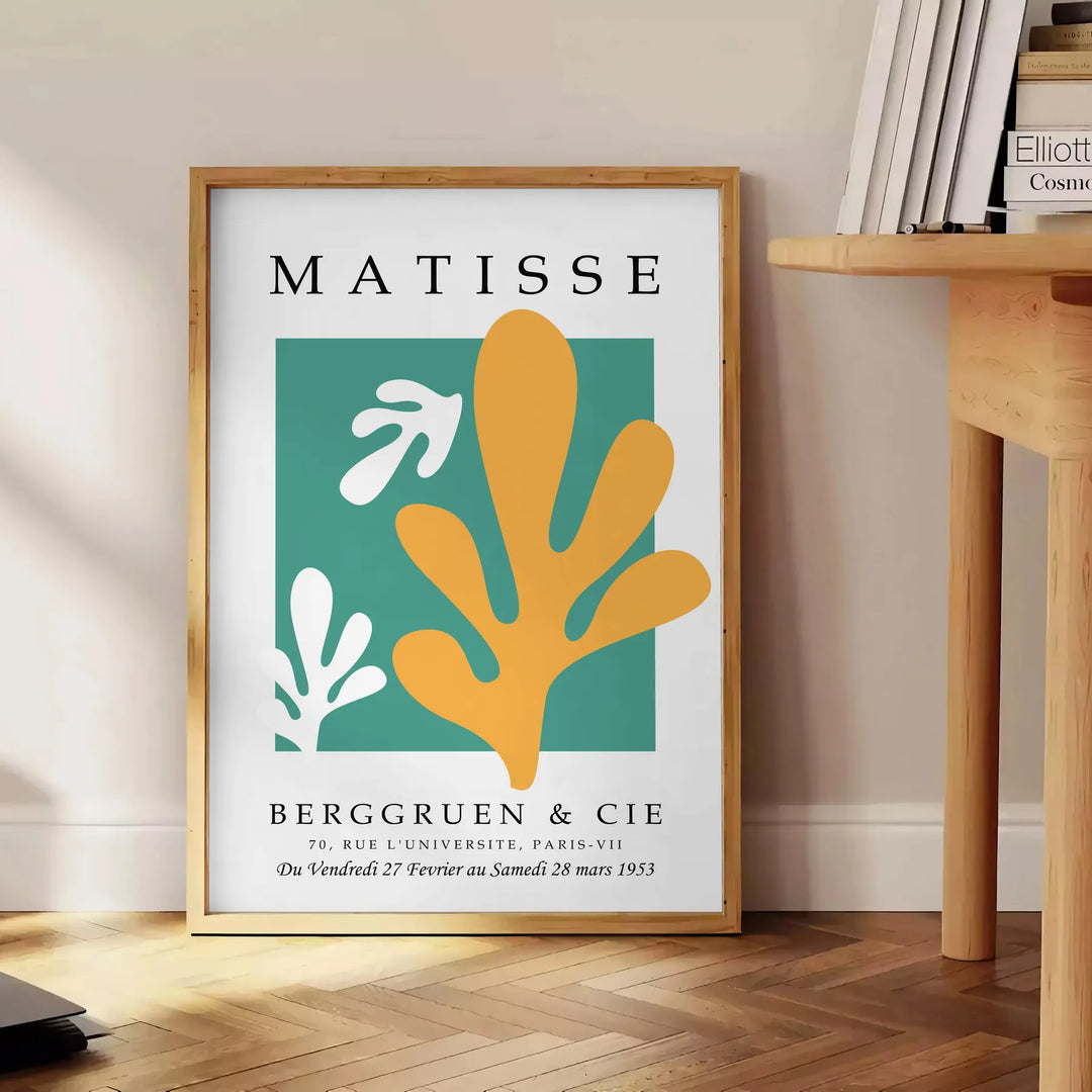 Abstract gray and white cut paper composition by Matisse - beside a round wooden side table with books