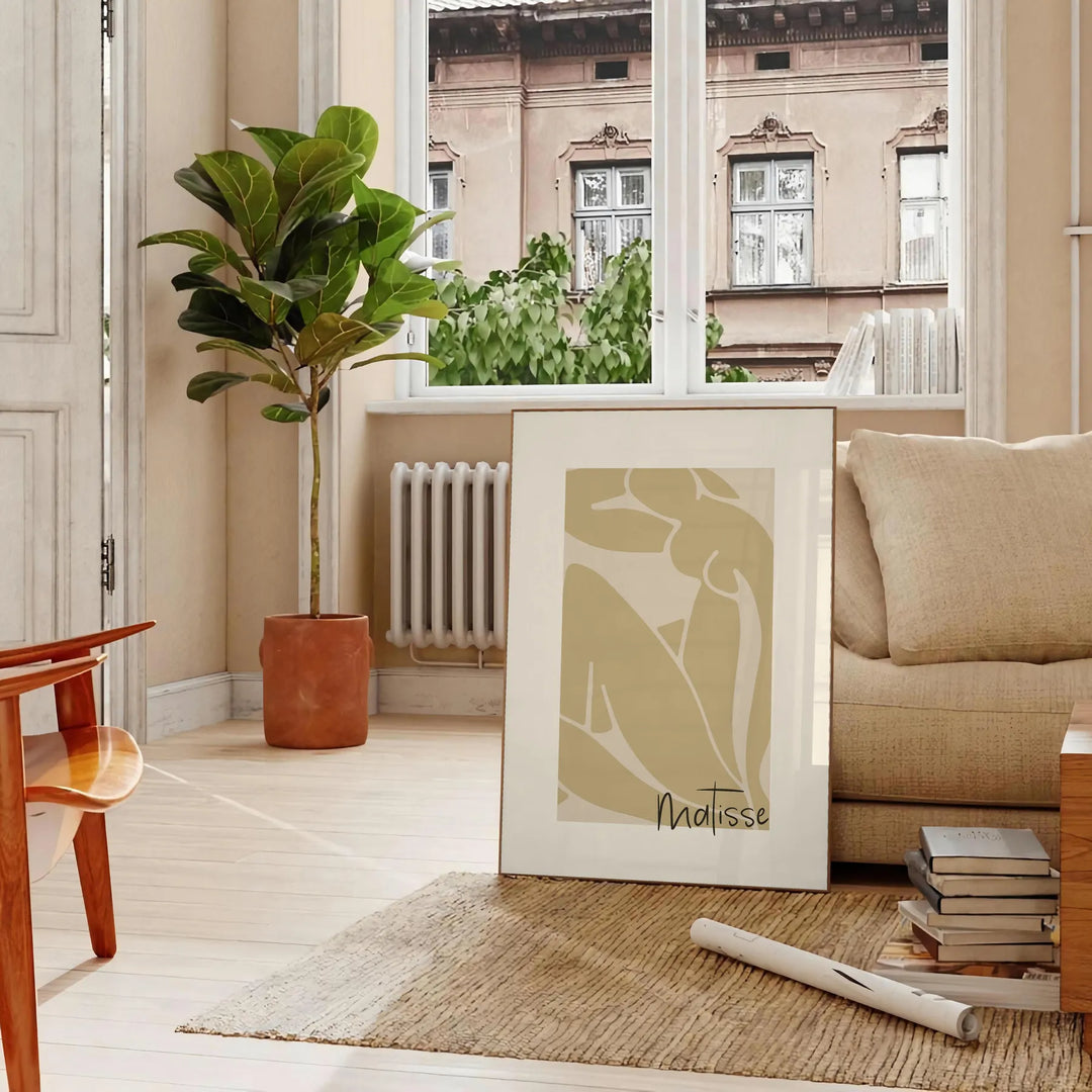 Henri Matisse paper cutouts in abstract shapes with gray and orange tones - in a Parisian living room with a sofa and a fig plant