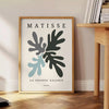 Gray and white Matisse papier découpé abstract poster in modern style. - beside a round wooden side table with books